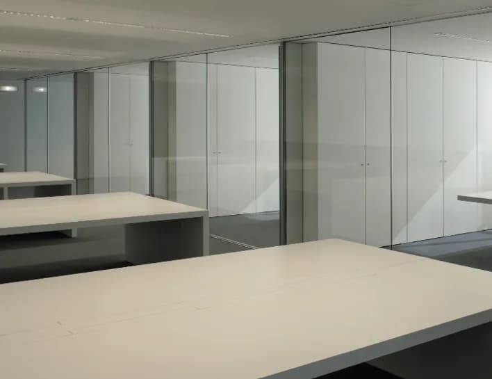 Ambiente interno com divisórias de vidro de perfis finos e bancadas claras