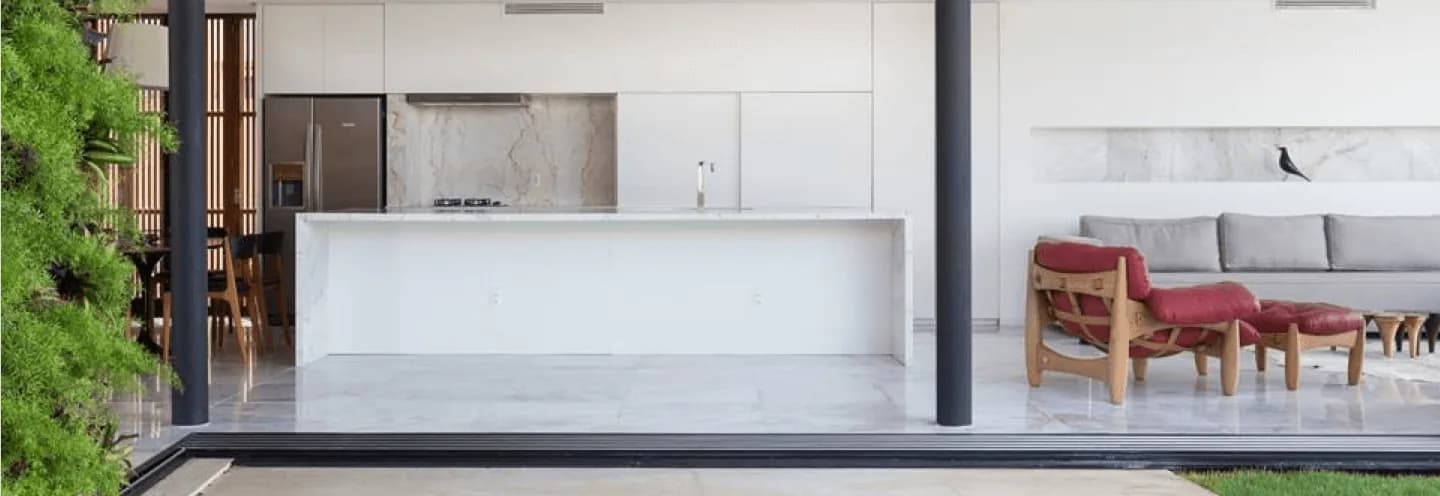 Cozinha integrada à sala com porta de correr de PVC branca da Linha Venezia aberta para o jardim